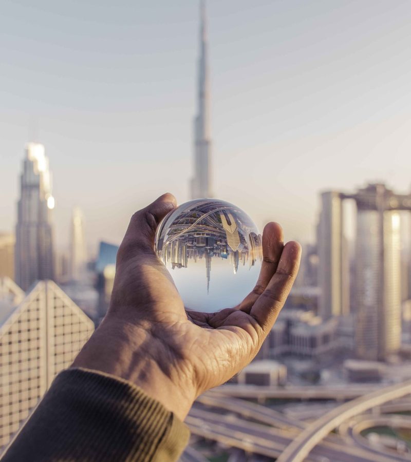 closeup-shot-male-hand-holding-crystal-ball-with-reflection-city-1.jpg